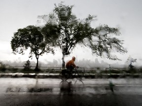A cyclist makes their way through the pouring rain along Saskatchewan Drive near 105 Street in Edmonton Monday July 13, 2020.
