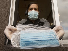 An employee at A&W  poses for a photo with packages of non-medical masks in the restaurant's drive-thru, in Edmonton Monday June 8, 2020.