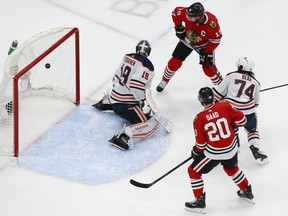 Jonathan Toews #19 and Brandon Saad #20 of the Chicago Blackhawks watch as a shot from teammate Connor Murphy (not pictured) gets past Mikko Koskinen #19 of the Edmonton Oilers for the go-ahead goal during the third period in Game 3 of the Western Conference Qualification Round at Rogers Place on August 05, 2020.