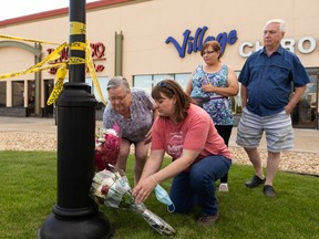 (Left to right) Nora Gueffroy, Janelle Bulloch, Lisa Tory and Les Gueffroy placed flowers as RCMP officers investigate a homicide at the Village Mall Clinic in Red Deer, south of Edmonton, on Monday, Aug. 10, 2020. A man was taken into custody.