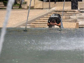 Shaun Reed washes in the fountain on a hot day at the Alberta Legislature as the temperature hit 31 degrees Celcius in Edmonton, on Monday, Aug. 17, 2020.