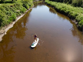 Kristine Doyle heads out along Whitemud Creek to paddle board on the North Saskatchewan River on a hot day in Edmonton, on Tuesday, Aug. 18, 2020.