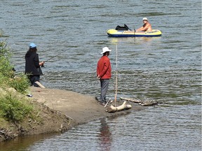 How's the fishing, as a man in a dinghy on the North Saskatchewan River passes two people fishing at the mouth of Whitemud Creek in Edmonton, August 28, 2020.