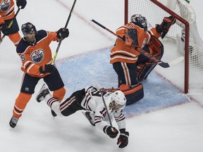 Oilers defenceman Darnell Nurse (25) checks Chicago Blackhawks forward Jonathan Toews (19) as goalie Mike Smith (41) makes the save during first period NHL playoff action in Edmonton, Saturday, Aug. 1, 2020.
