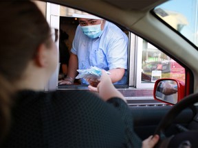 Masks are handed out at McDonald’s drive-through in Calgary on Wednesday, June 10, 2020.