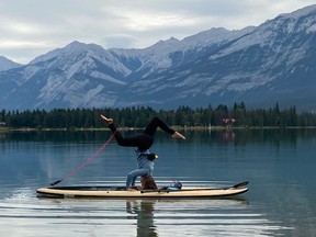 Alisen Charlten stands on her head on a stand-up paddleboard in Jasper.