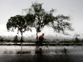 A cyclist makes their way through the pouring rain along Saskatchewan Drive near 105 Street in Edmonton Monday July 13, 2020. Photo by David Bloom