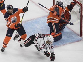 Edmonton Oilers' Darnell Nurse checks Chicago Blackhawks' Jonathan Toews as goalie Mike Smith makes the save during first period NHL playoff action in Edmonton, Aug. 1, 2020.
