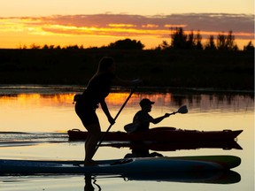 A standup paddle boarder and a kayaker paddle the Sturgeon River near St. Albert as the sun sets northwest of Edmonton, on Wednesday, Sept. 9, 2020.