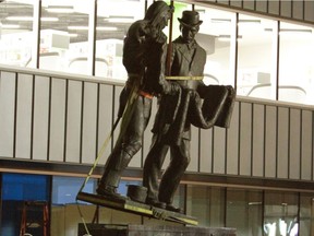 A crew from Wilco working for the City of Edmonton. removes John Weaver's The Trader from behind the Stanley Milner library in the early morning hours of Saturday.