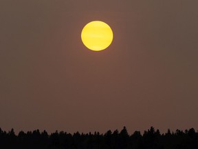 A couple chat as a hazy sun sets over the river valley in Edmonton, on Thursday, Sept. 17, 2020. Wildfire smoke has made for hazy, smoky skies across North America.