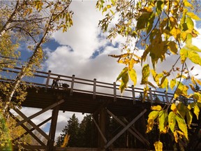 Edmontonians take in fall colours while walking over a trestle bridge through Mill Creek Ravine Park in Edmonton, on Sunday, Sept. 27, 2020.