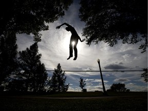 Daniel Anderson leaps in the air as he slacklines in Constable Ezio Faraone Park, in Edmonton Thursday Sept. 3, 2020. Anderson was jumping into the air from the slackline and landing back on the line.