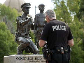 Const. Collin Smart visits the statue of Const. Ezio Faraone in Const. Ezio Faraone Park after it was vandalized with spray paint in Edmonton on Sept. 4, 2020. The spray paint was quickly removed.