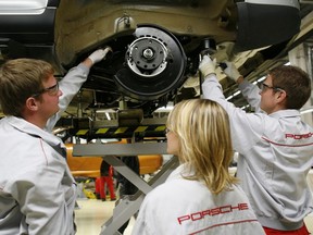 Apprentices of German sports car maker Porsche work on a car at the Porsche Leipzig GmbH plant in Leipzig.