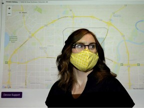 A GPS tracking program is projected on the background as MacEwan University project team member Heather Braid poses for a photo following the university's winning submission to the Edmonton Police Foundation's  Community Solutions Accelerator program challenge concerning liquor store thefts on Tuesday, Sept. 15, 2020.