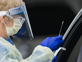A health-care worker does testing at a drive-thru COVID-19 assessment centre at the Etobicoke General Hospital in Toronto on Tuesday, April 21, 2020.