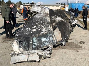 This handout photograph taken and released on January 11, 2019, by The National Security and Defense Council of Ukraine, shows people standing and analysing the fragments and remains of the Ukraine International Airlines plane Boeing 737-800 that crashed outside the Iranian capital Tehran on January 8, 2020.