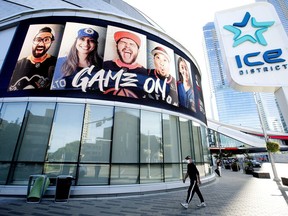 A pedestrian wearing a face mask walks past Rogers Place, one of the NHL's Stanley Cup playoff hub cities, in Edmonton Monday Aug. 10, 2020. The Edmonton Oilers Community Foundation is holding 50/50 draws for the Stanley Cup Finals.