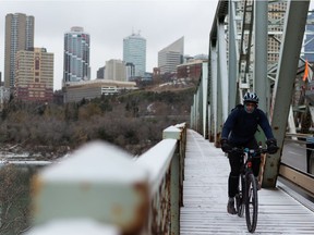 A cyclist crosses the Low Level Bridge as snow falls in Edmonton, on Monday, Oct. 19, 2020.