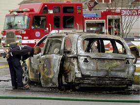 A fire investigator examines a burned out vehicle near 37A Avenue and 9 Street in Edmonton on Tuesday, Oct. 20, 2020.