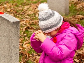 This young lady at the Leave No Stone Alone did what organizer Maureen Bianchini-Purvis hoped she would do at last year;s Edmonton service - she prayed for a military veteran who had lost his life fighting for Canada. (Photo by Gord Deeks)