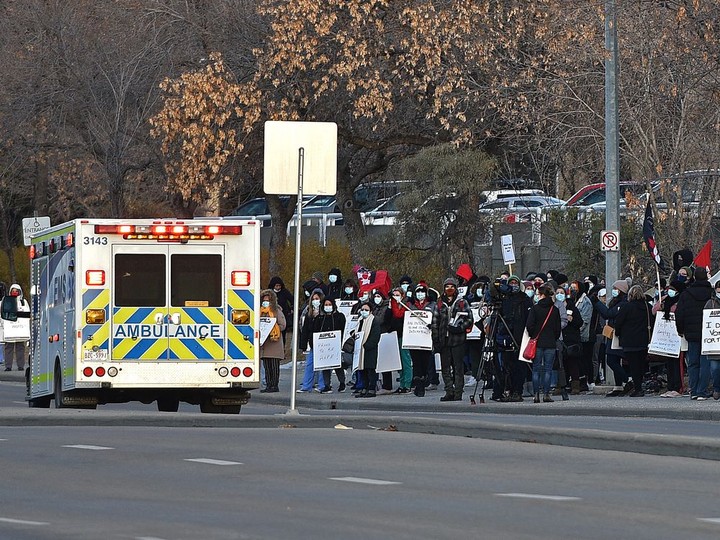 An ambulance on a call passes health-care workers who have walked off the the job outside the Royal Alexandra Hospital joining others at various health care locations across Alberta on Monday, Oct. 26, 2020. Ed Kaiser/Postmedia