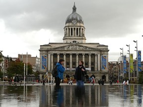 People wearing protective face covering to combat the spread of coronavirus covid-19 talk in front of the Town Hall in Nottingham in central England on October 9, 2020. - Pubs and restaurants in coronavirus hotspots look set to face fresh restrictions after Downing Street said new data suggests there is "significant" transmission taking place in hospitality settings. A "range of measures" is being looked at, with a particular focus on northern England, where it says infection rates are rising fastest. (Photo by Oli SCARFF / AFP)