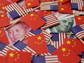 A U.S. dollar banknote featuring American founding father Benjamin Franklin and a China's yuan banknote featuring late Chinese chairman Mao Zedong are seen among U.S. and Chinese flags.