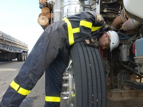 An officer with Alberta Transportation's Commercial Vehicle Enforcement branch checks the brake pots on a logging truck during a vehicle inspection blitz Tuesday at the weigh scales north of Grande Prairie. File photo.