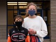 Two children wearing masks in front of a school.