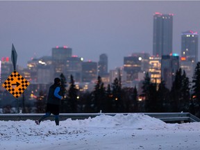 A runner heads past a city scape at 75 Street and Ada Boulevard at nightfall in Edmonton, on Tuesday, Nov. 17, 2020.