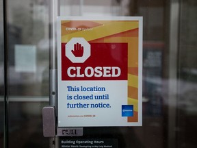 A sign on the front entrance informs visitors to Edmonton City Hall that the building has been closed to the public, Nov. 23, 2020. Rules around restaurants, one-on-one fitness training, and children's sports are changing starting Monday as Alberta takes its first step to reopen after a deadly second wave of COVID-19.