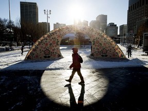 A pedestrian walks past an arch set up in Churchill Square as part of The Works Art & Design Festival, in Edmonton Wednesday Nov. 25, 2020. The installation, by artists Sharon Rose Kootenay and Jason Symington, is titled Transformation: Promise and Wisdom. Although the festival was canceled this year due to COVID-19, organizers continuing to present online activities and art set up in public spaces.