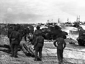 Troops from the Royal Winnipeg Rifles and Regina Rifles, after establishing a beahead on Juno Beach on June 6, 1944, watch as tanks of the 1st Hussars land to join the fight to free western Europe from Nazi occupation.
