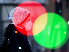 A pedestrian wearing a face mask walks past the Christmas lights in Dr. Wilbert McIntyre Park, 8331 104 St., in Edmonton Sunday Dec. 20, 2020.