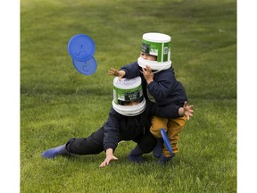 Lew Conklin,5, (left) and little brother Koen, 3, (right) play play frisbee with their mom with food container lids while wearing robot heads which are made from sour cream containers in a downtown park on Friday, May 29, 2020  in Edmonton.