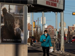 A masked walker passes a message about takeout coffee products at Transcend Coffee at 8708 109 Street in Edmonton, on Sunday, Dec. 6, 2020. Many business have pivoted to take out and home delivery options as the public health orders imposed during the COVID-19 pandemic.