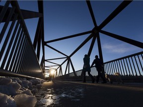 Walkers take advantage of the warm weather as they walk across the Hawrelak Park foot bridge on Wednesday, Dec. 9, 2020 in Edmonton.