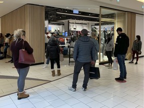 Shoppers line up at a store in Southgate Centrel on Friday, Dec. 11, 2020 in Edmonton. With new COVID-19 restrictions  going into effect Sunday in Alberta some shoppers are taking advantage of the last days of looser retail rules.