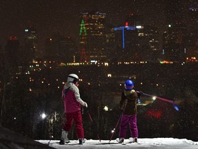 Night time skiers just getting off the lift during a snowfall as the city lights are still visible at the top of the Edmonton Ski Club, December 14, 2020.