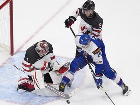 Canada's goalie Devon Levi (1) stops the puck with teammate Thomas Harley (5) as Slovakia's Dominik Jendek (14) can't get the puck during second period IIHF World Junior Hockey Championship action on Sunday, Dec. 27, 2020 in Edmonton.