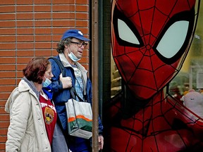 Spiderman keeps an eye on two pedestrians walking past a store front on Whyte Avenue in Edmonton on Monday December 7, 2020. (Photo by Larry Wong/Postmedia)