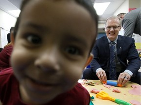 A toddler stares into the camera as the Associate Minister of Red Tape Reduction, Grant Hunter, plays with kids at the Kids3 Daycare, in Edmonton Tuesday Feb. 4, 2020. Hunter was at the daycare to take part in the announcement of a new online application process for child care subsidies.