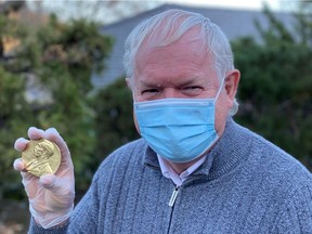 Nobel Prize in Medicine winner British scientist Michael Houghton holds his medal outside his home in Danville, San Francisco, U.S., in this handout image obtained by Reuters on Dec. 8, 2020.