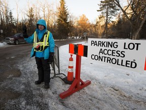 Duane Schade stands at the entrance to the Victoria Park parking lot on Saturday, Dec. 12.  He works for the city and is making sure that there are no more than 70 cars in the lot. Other city employees watched to make sure that groups of people are not gathering on the rink or in the pavilion.