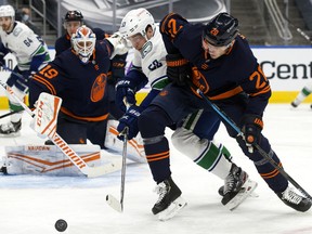 The Edmonton Oilers' Slater Koekkoek (20) battles the Vancouver Canucks' Bo Horvat (53) in Edmonton on Thursday, Jan. 14, 2021.