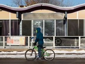 A cyclist in a COVID-19 mask passes the closed Hilltop Pub  in Edmonton, on Thursday, Jan. 14, 2021. Pubs and restaurants have been temporarily closed for in person service by the government due to the pandemic.