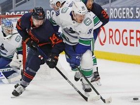 Edmonton Oilers forward Devin Shore (14) and Vancouver Canucks defensemen Nate Schmidt (88) battle for a loose puck during the third period at Rogers Place.