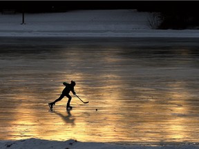 As the sun sets, light schimmers off the ice surface as a hockey players skates across at Hawrelak Park in Edmonton, January 19, 2021.